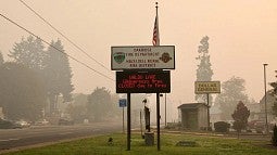 signs for oakridge fire department with smoky sky in background