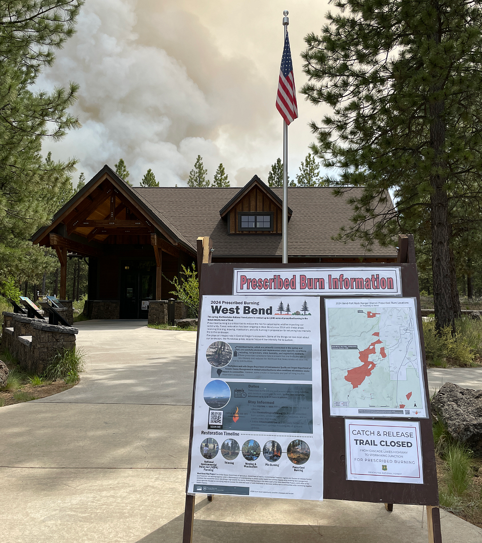 Sandwich board with signs with prescribed burn information, map, and trail closures notice. 