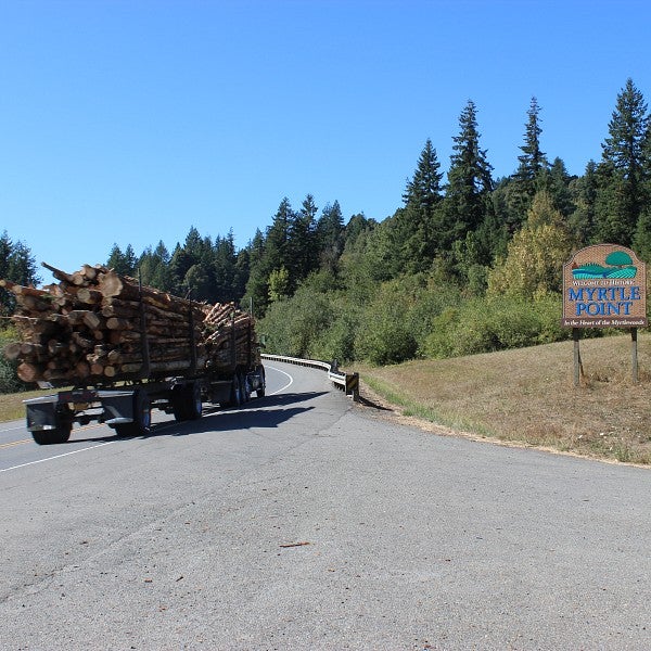 logging truck passing myrtle point sign